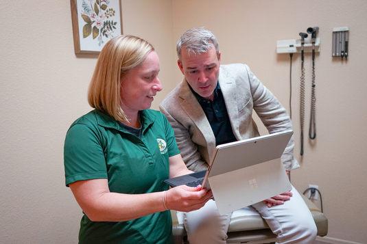 A medical provider showing a patient information on a notebook computer.